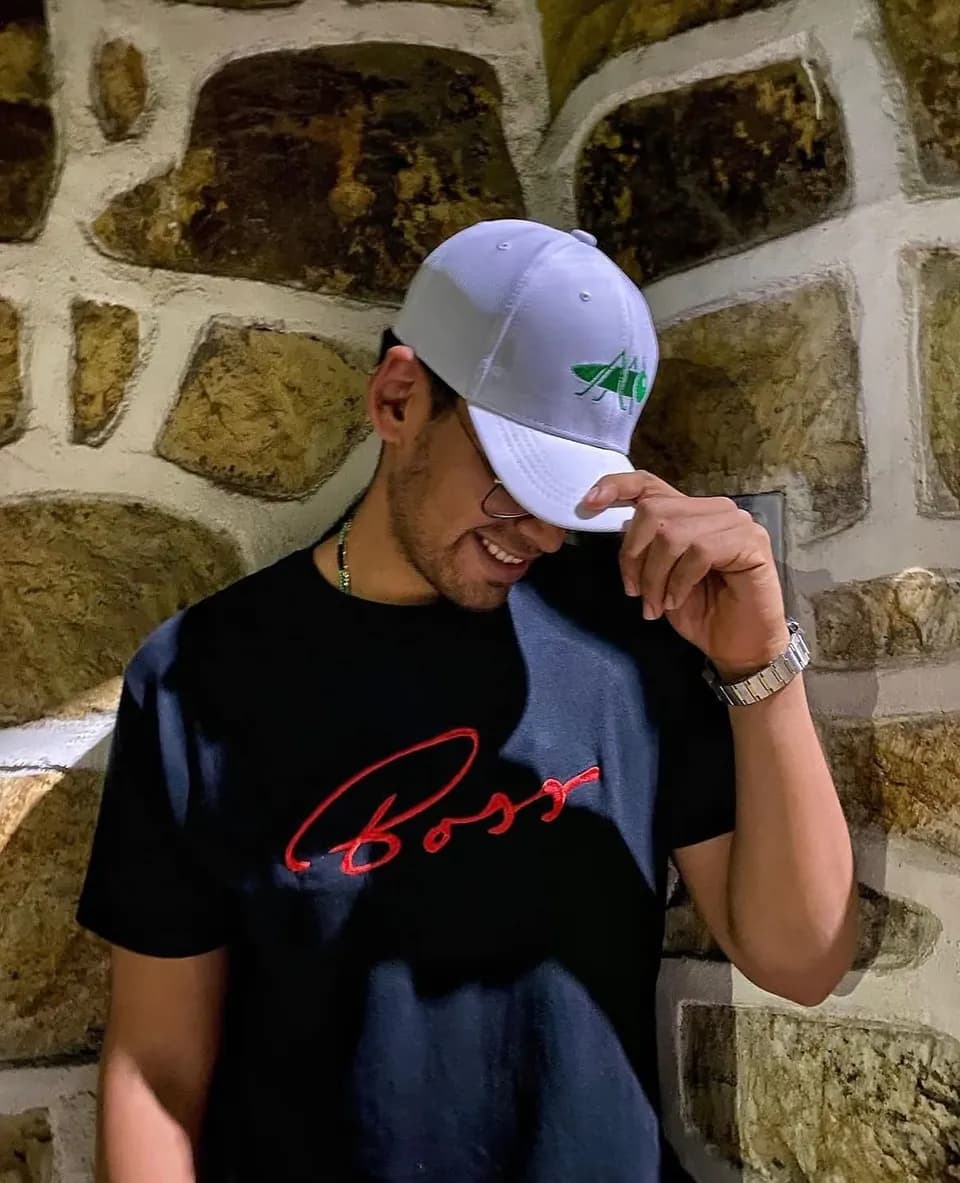 Modelo usando una gorra bordada junto a un muro de piedra